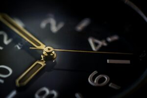 Detailed macro shot of an analog wristwatch showing gold hands and blurred numerals.