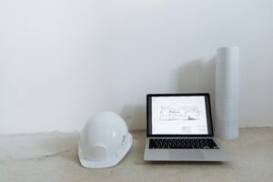 A clean workspace with laptop, hard hat, and blueprints for construction planning.